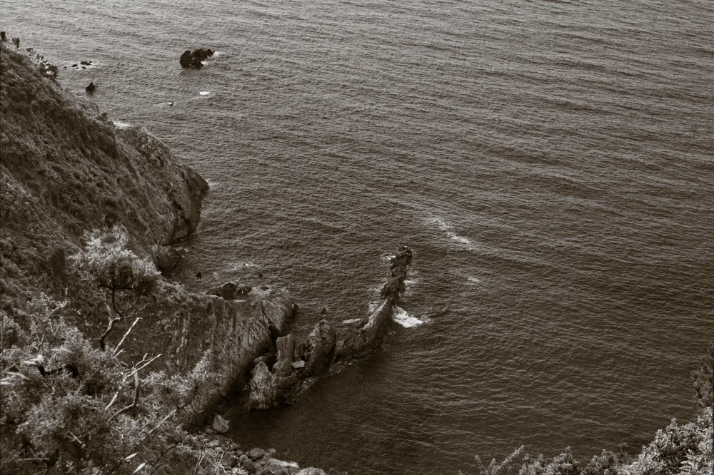 Punta rocosa entrando en el mar, virada en sepia